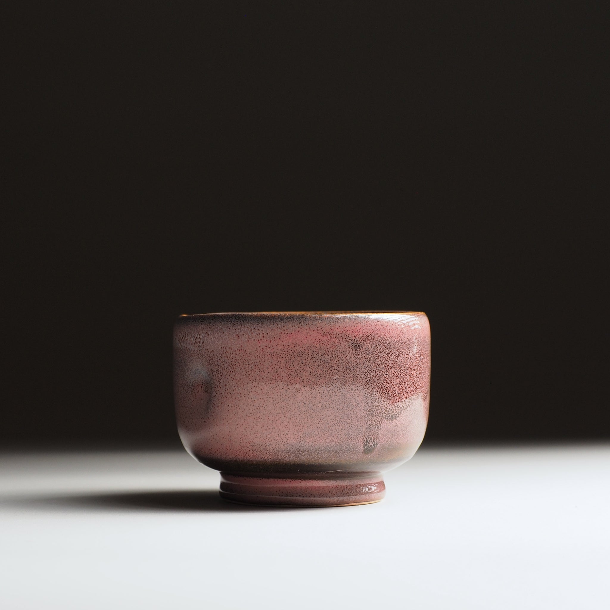 front view of a Japanese pink ceramic teacup on a dark background