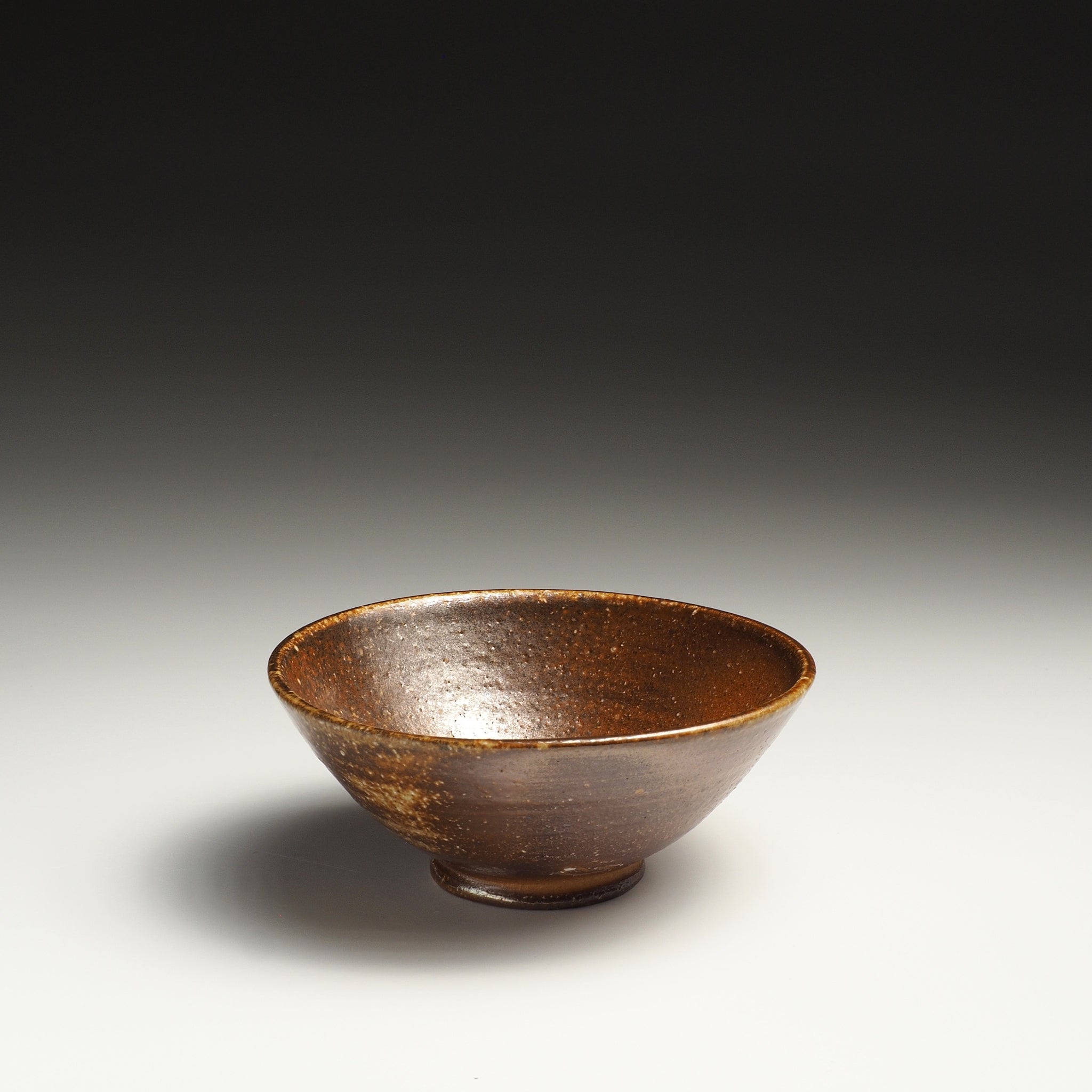 Single Mizuho handmade Shigaraki rice bowl showing its rounded form and dark brown interior.