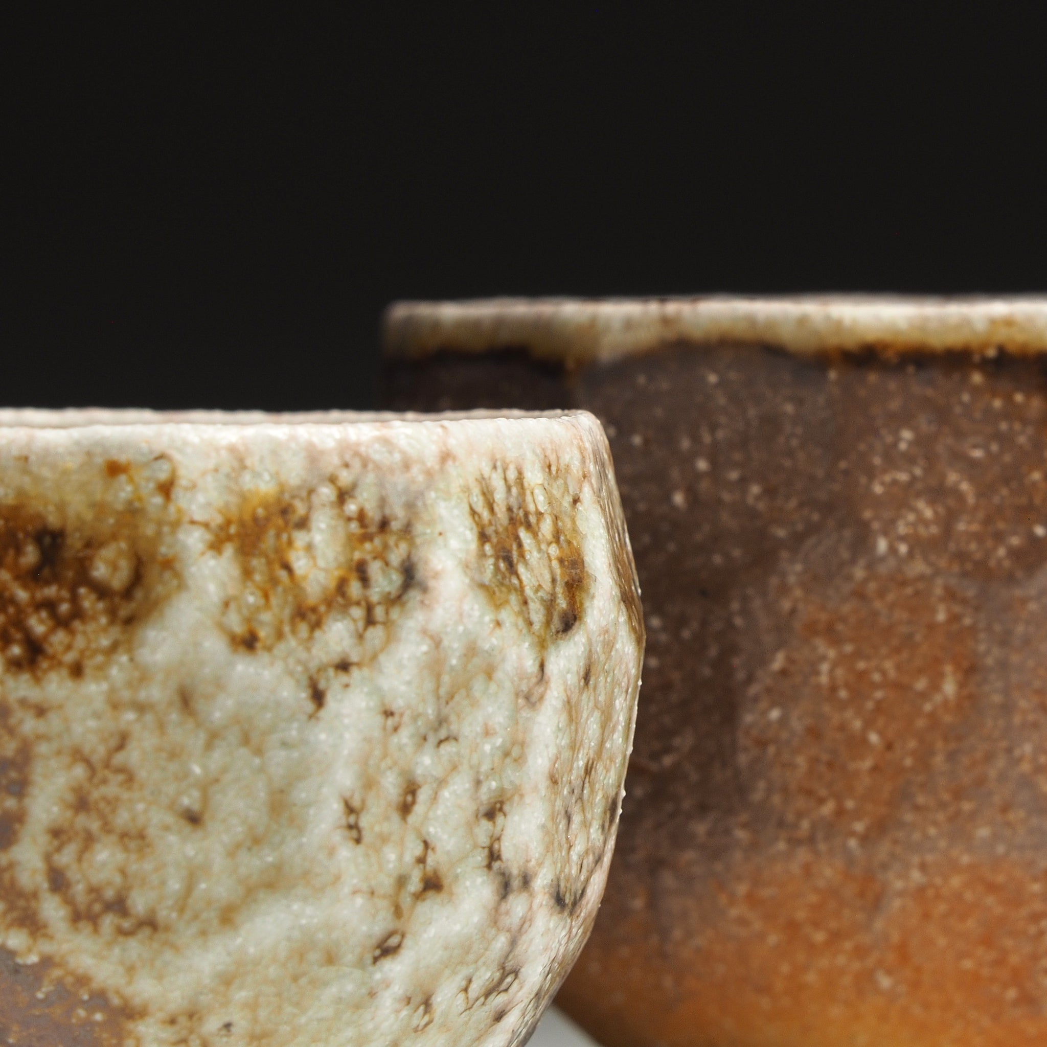 Close-up of the smaller Ryoen handmade Shigaraki yunomi with mottled beige glaze, with the larger cup softly visible in the background.