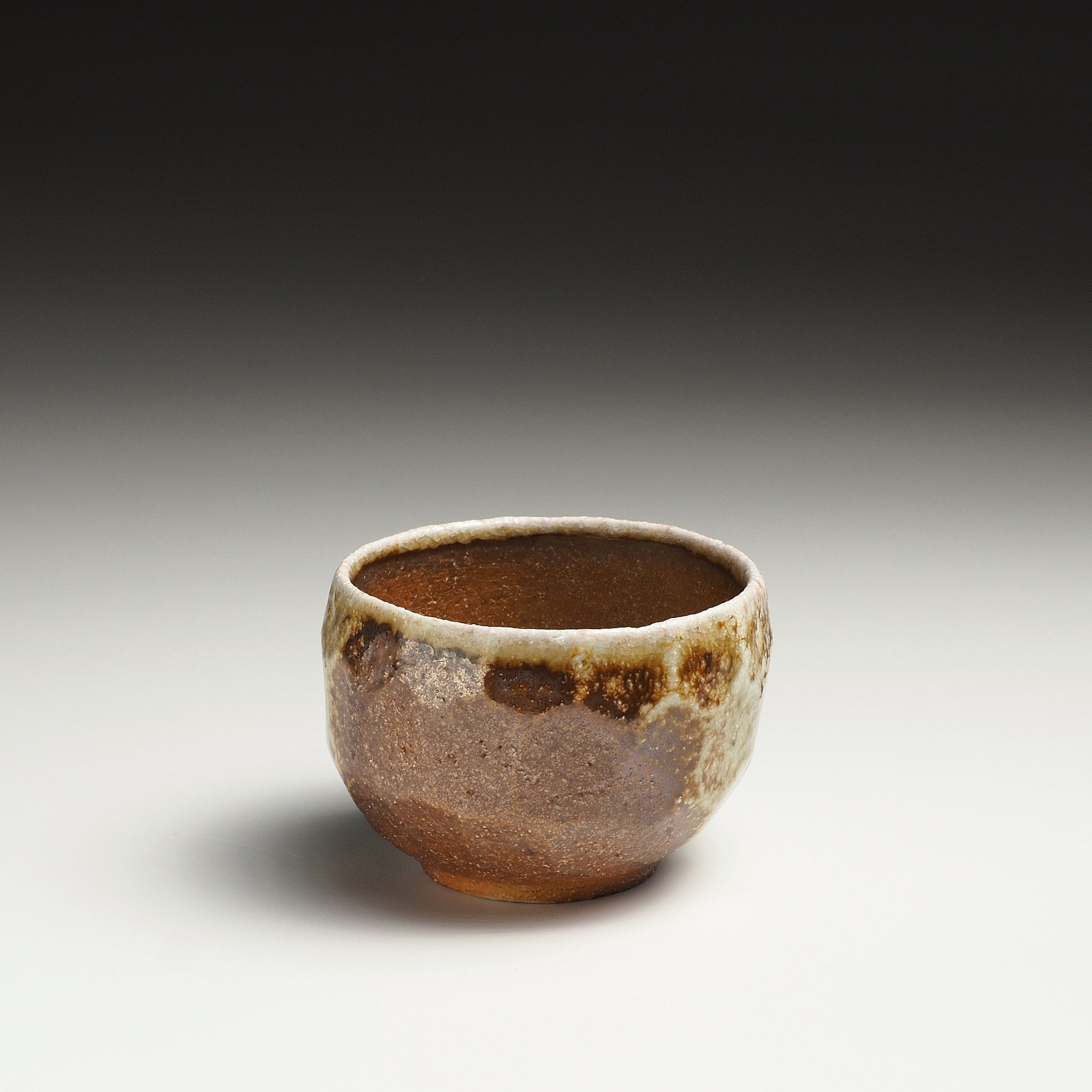 Single Ryoen handmade Shigaraki yunomi with warm brown clay and irregular beige glaze around the upper body.