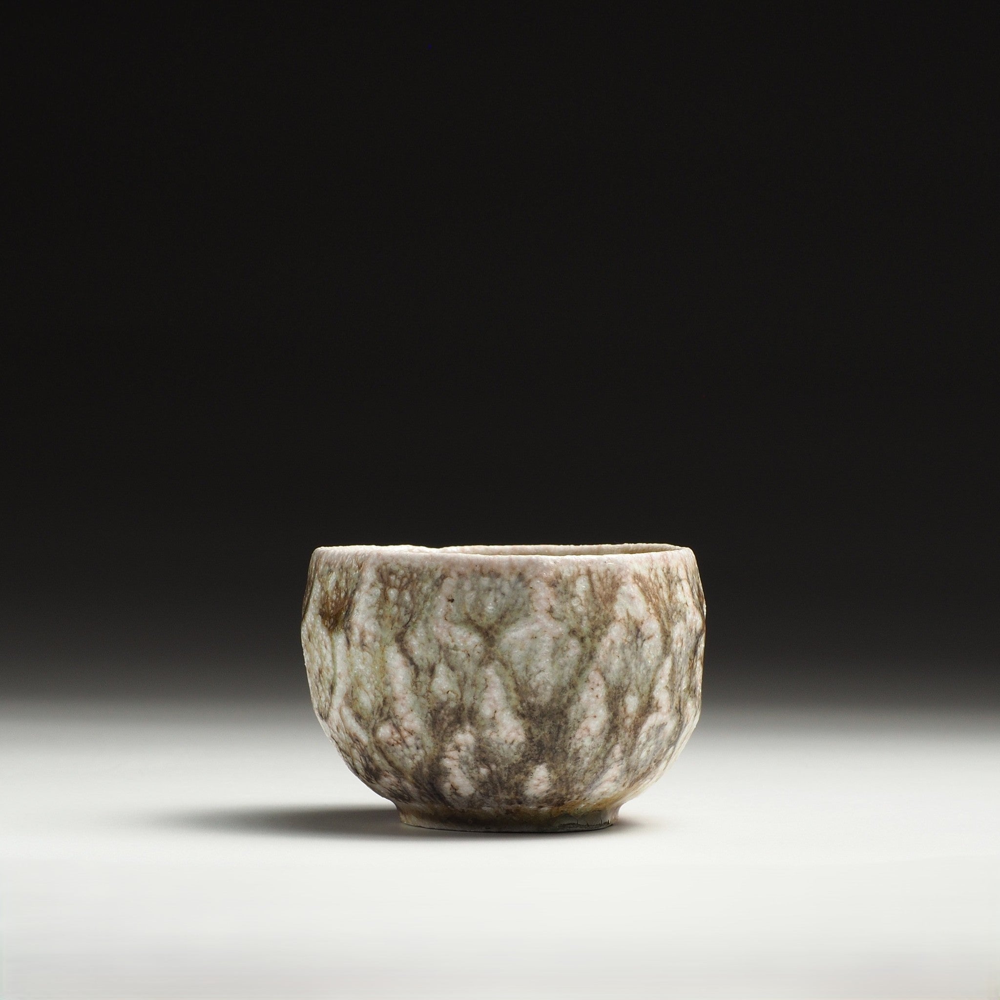 Front view of a Ryoen handmade Shigaraki yunomi with a heavily mottled beige and gray glaze.