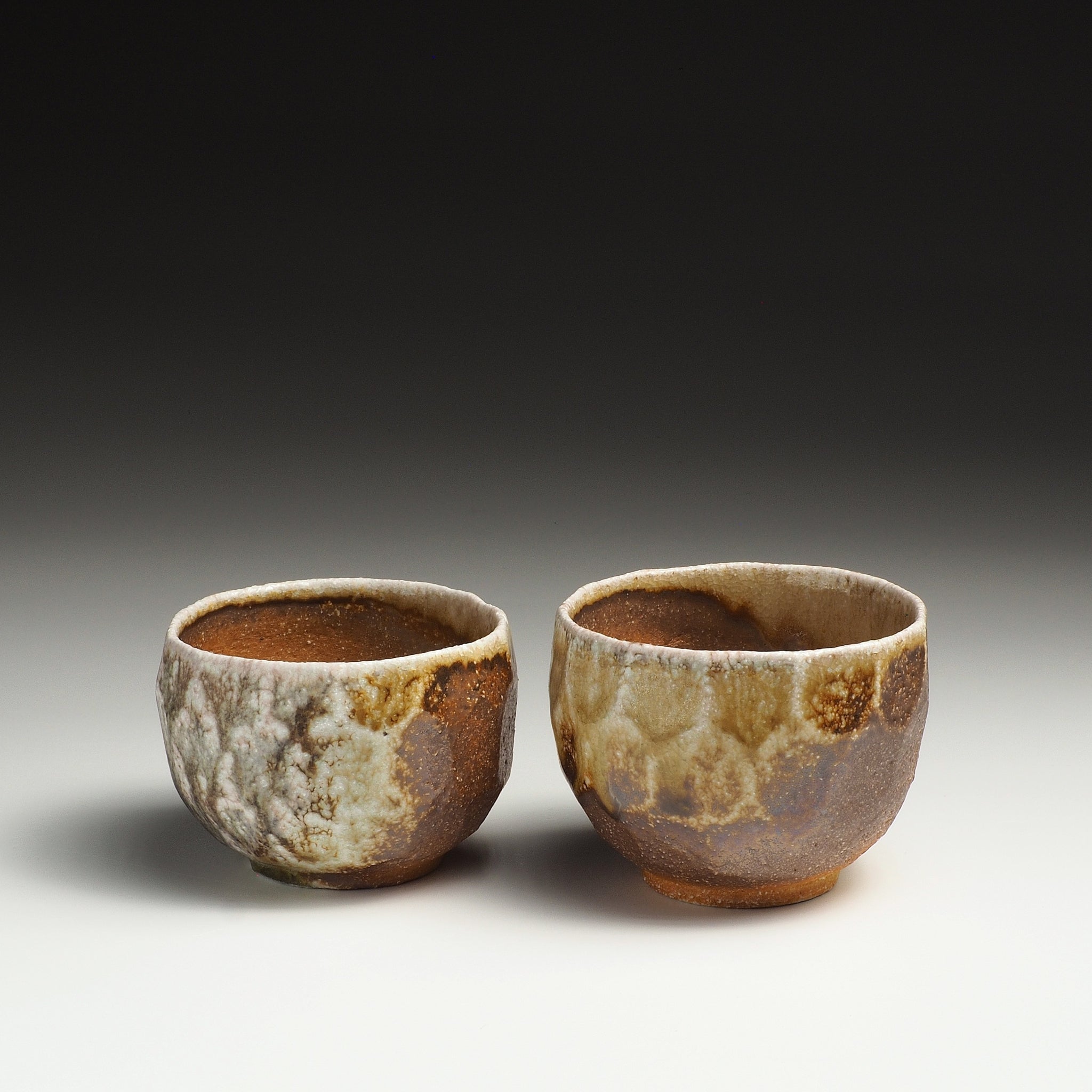 Two Ryoen handmade Shigaraki yunomi teacups side by side with contrasting earthy mottled surfaces.
