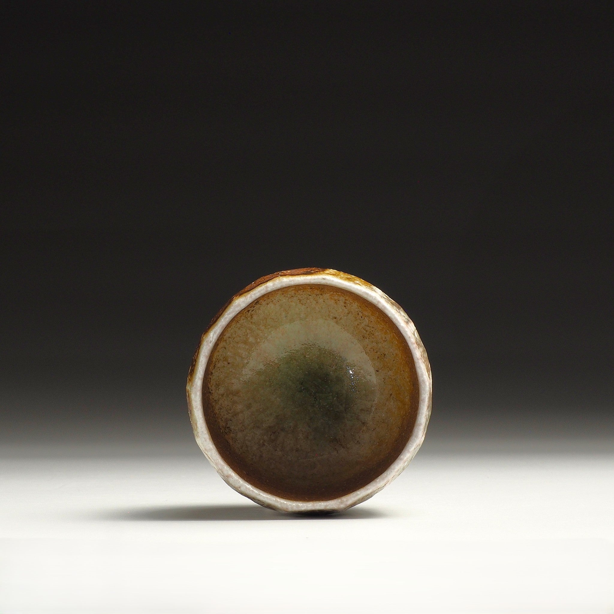 Interior view of a Ryoen handmade Shigaraki yunomi with natural emerald-green glaze pooled at the bottom of the cup.