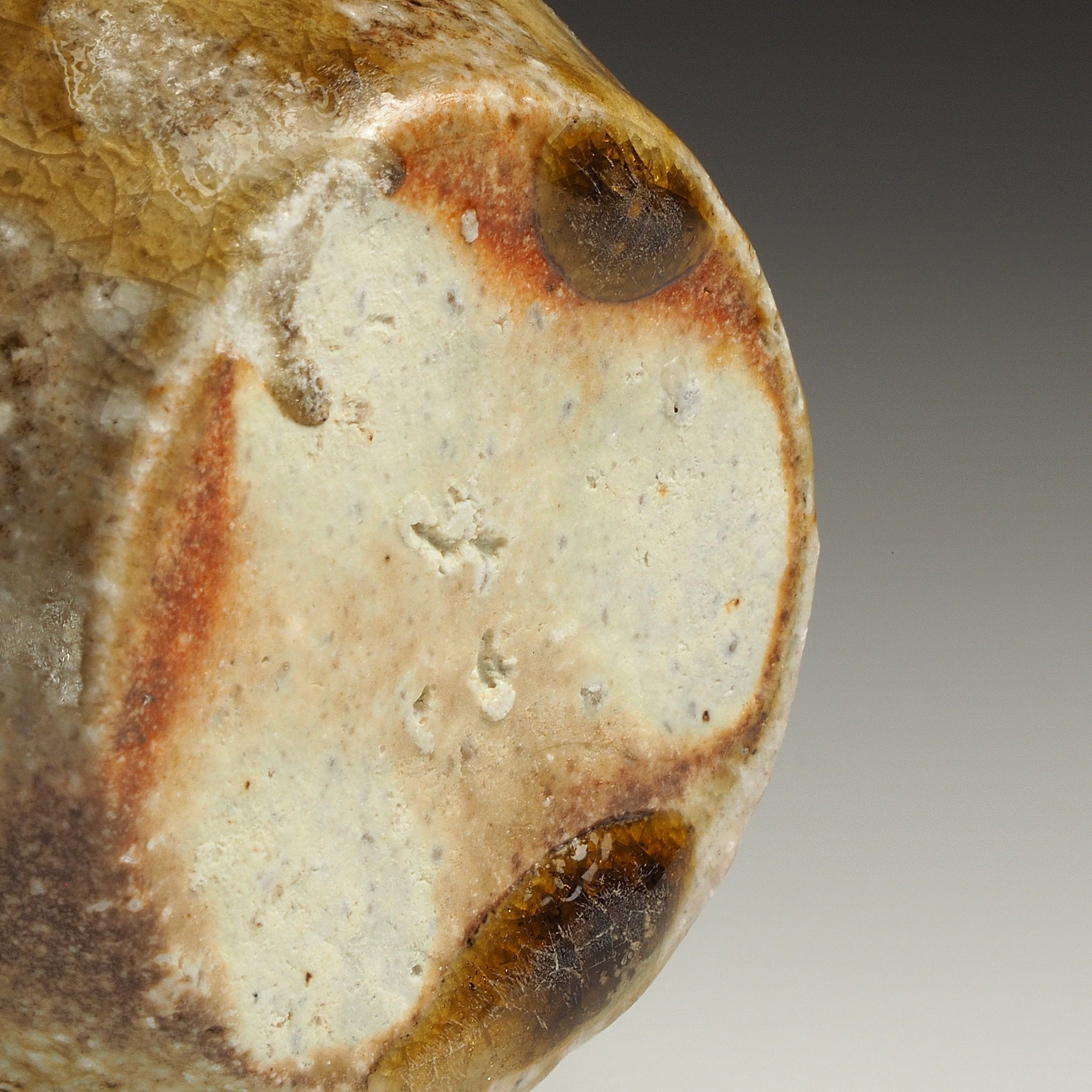 Close-up of the base of the Setsugan Shigaraki flower vase showing the pale foot and natural orange-brown firing marks.