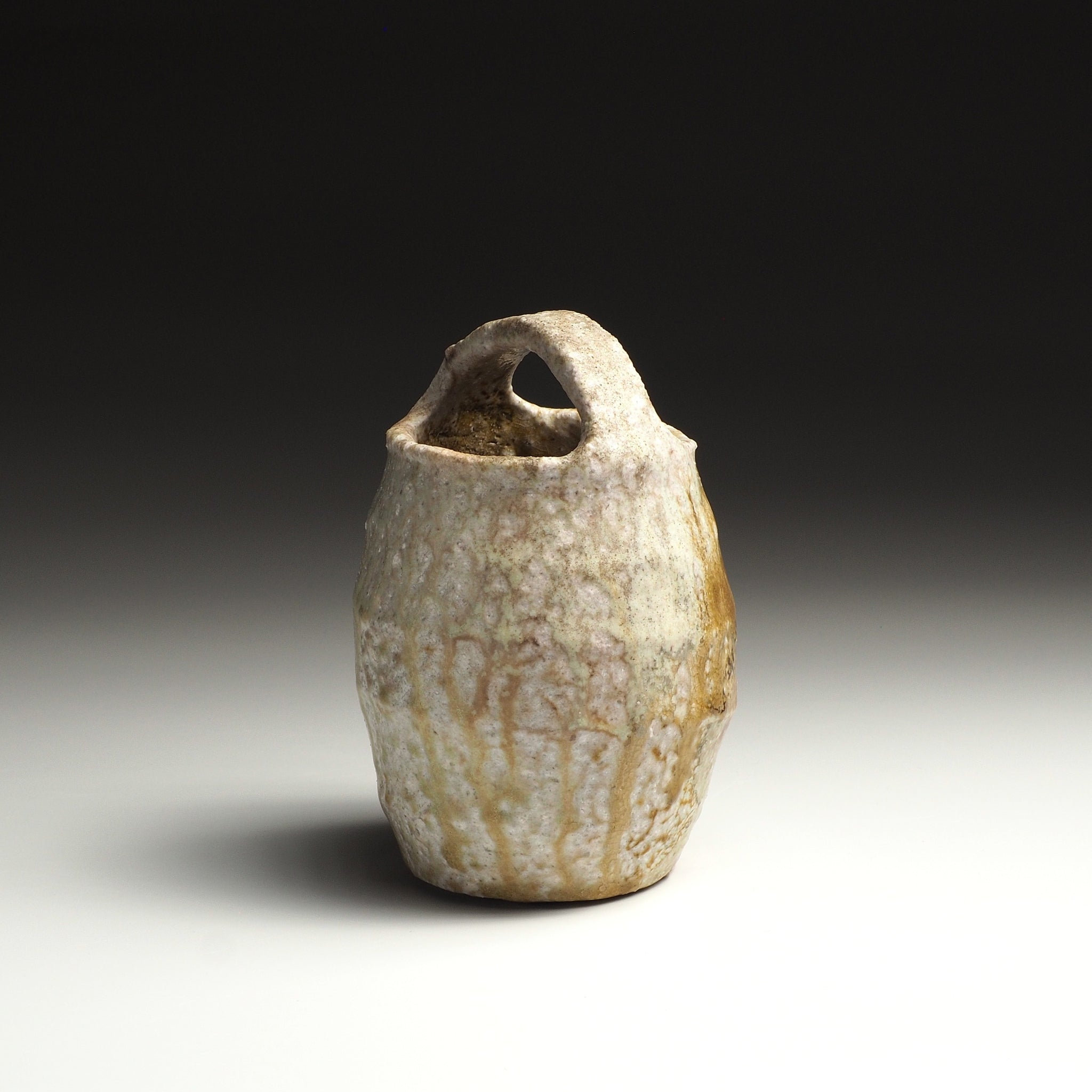 Setsugan handmade Shigaraki flower vase viewed at an angle, showing its loop handle and softly irregular form.