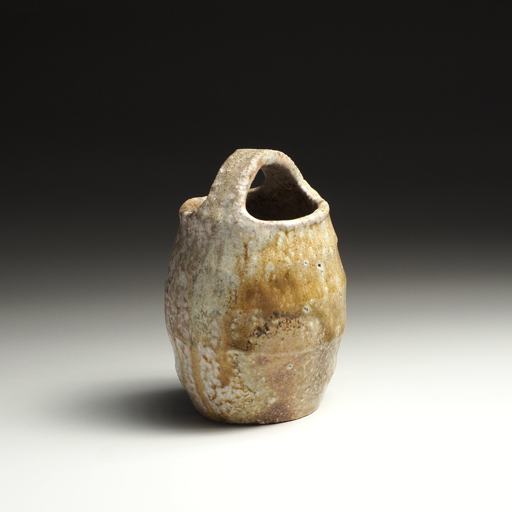 Setsugan handmade Shigaraki flower vase with a tall rounded form, loop handle, and natural beige and brown ash-fired surface.
