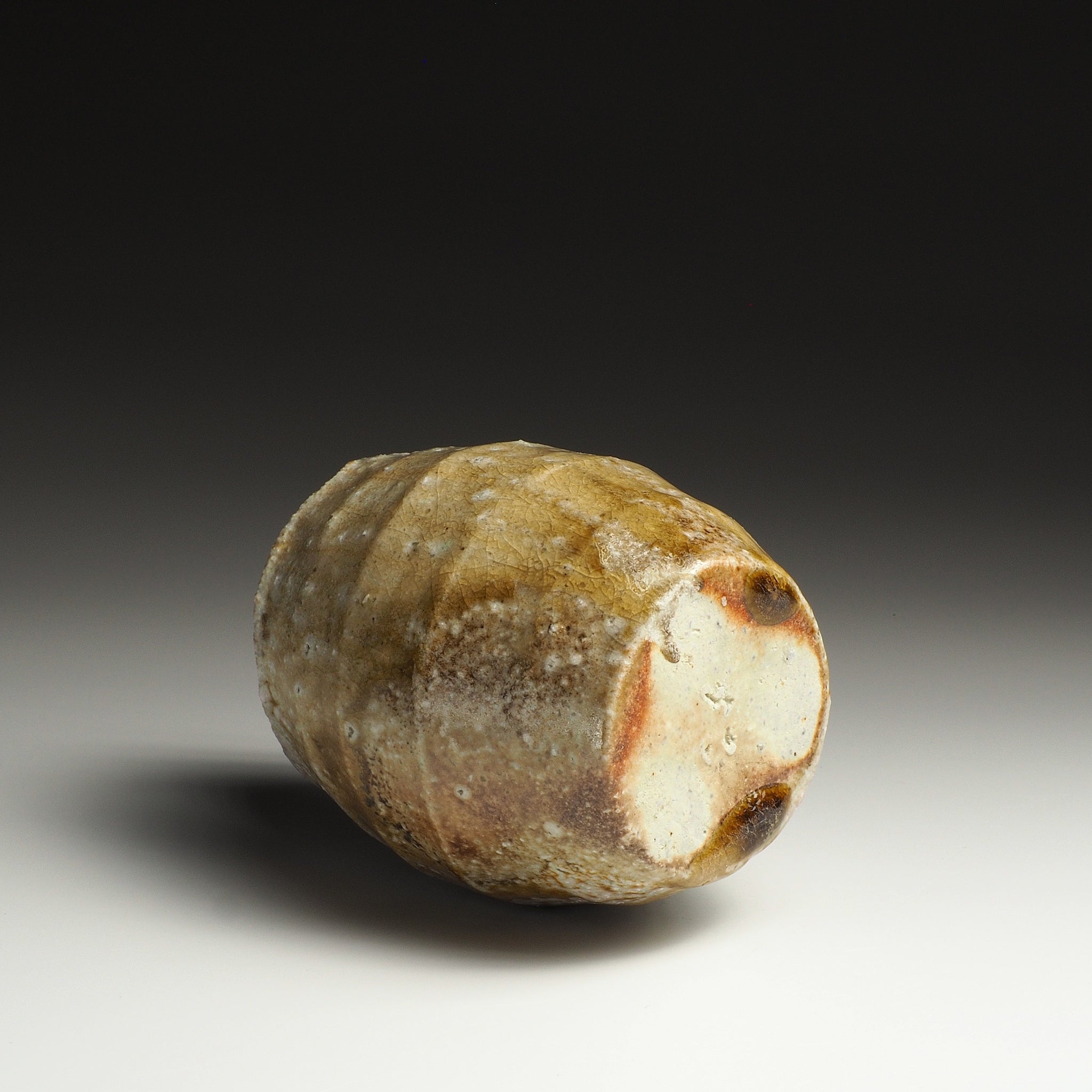 Setsugan Shigaraki flower vase resting on its side, showing the base and natural orange, beige, and brown firing marks.