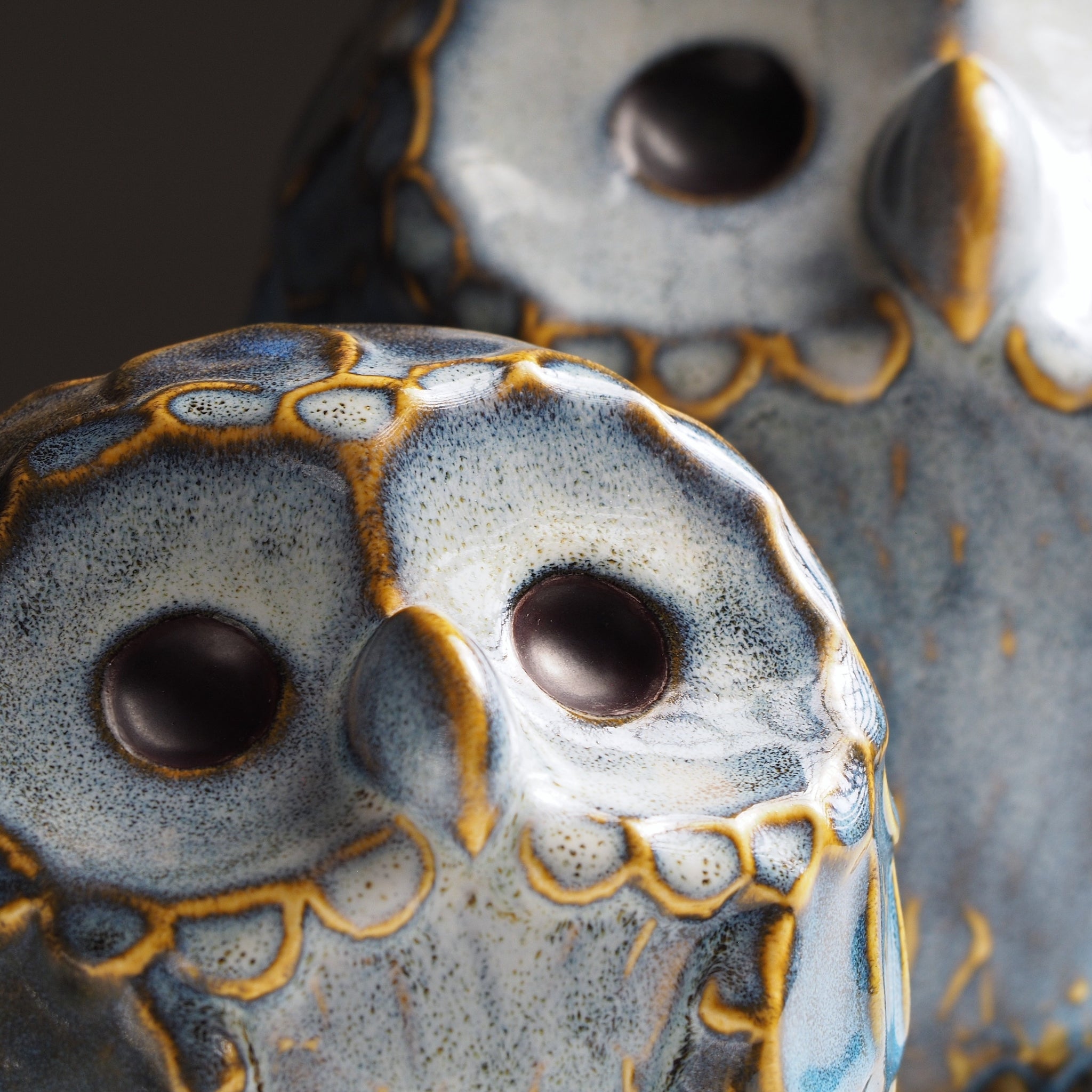 Close-up of the smaller Sofuku ceramic owl ornament with the larger owl softly visible behind it