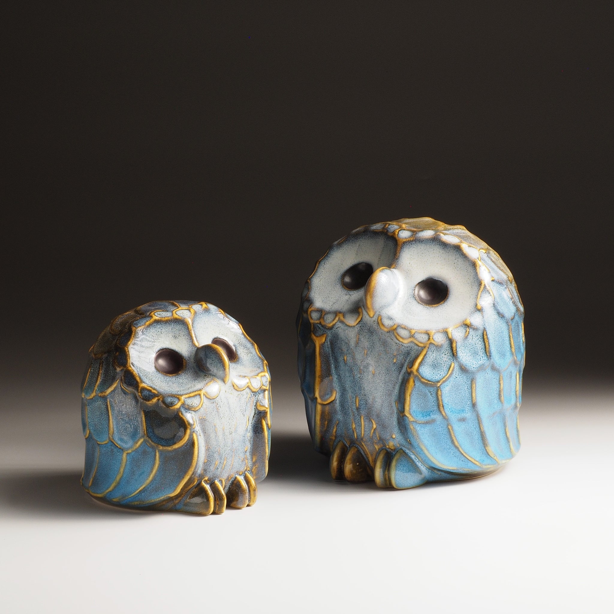 Front view of the Sofuku pair of small and medium owl-shaped ceramic ornaments with blue and gold glaze