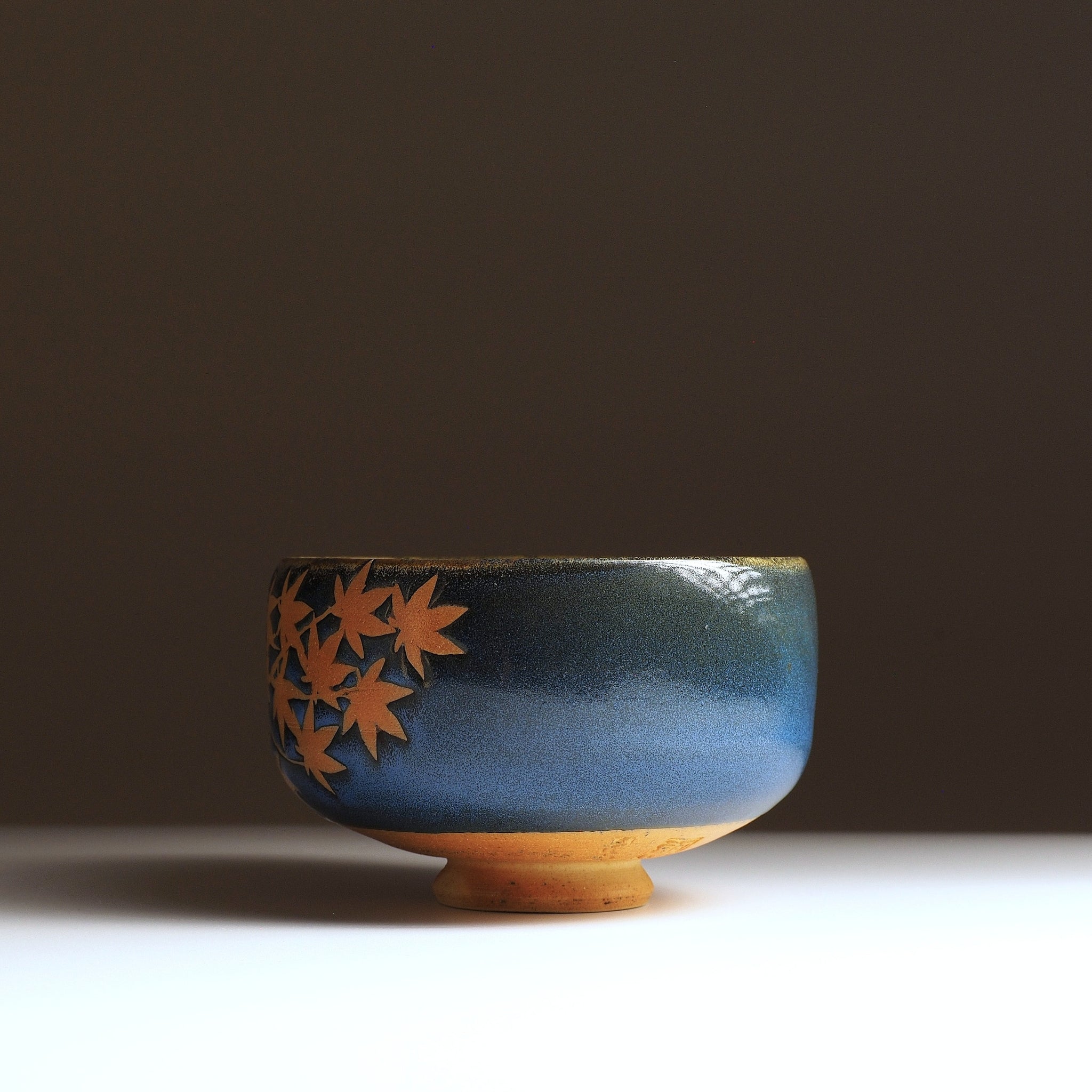Sōshū matchawan, side view, momiji cluster in natural clay on blue Nanasai Tenmoku glaze