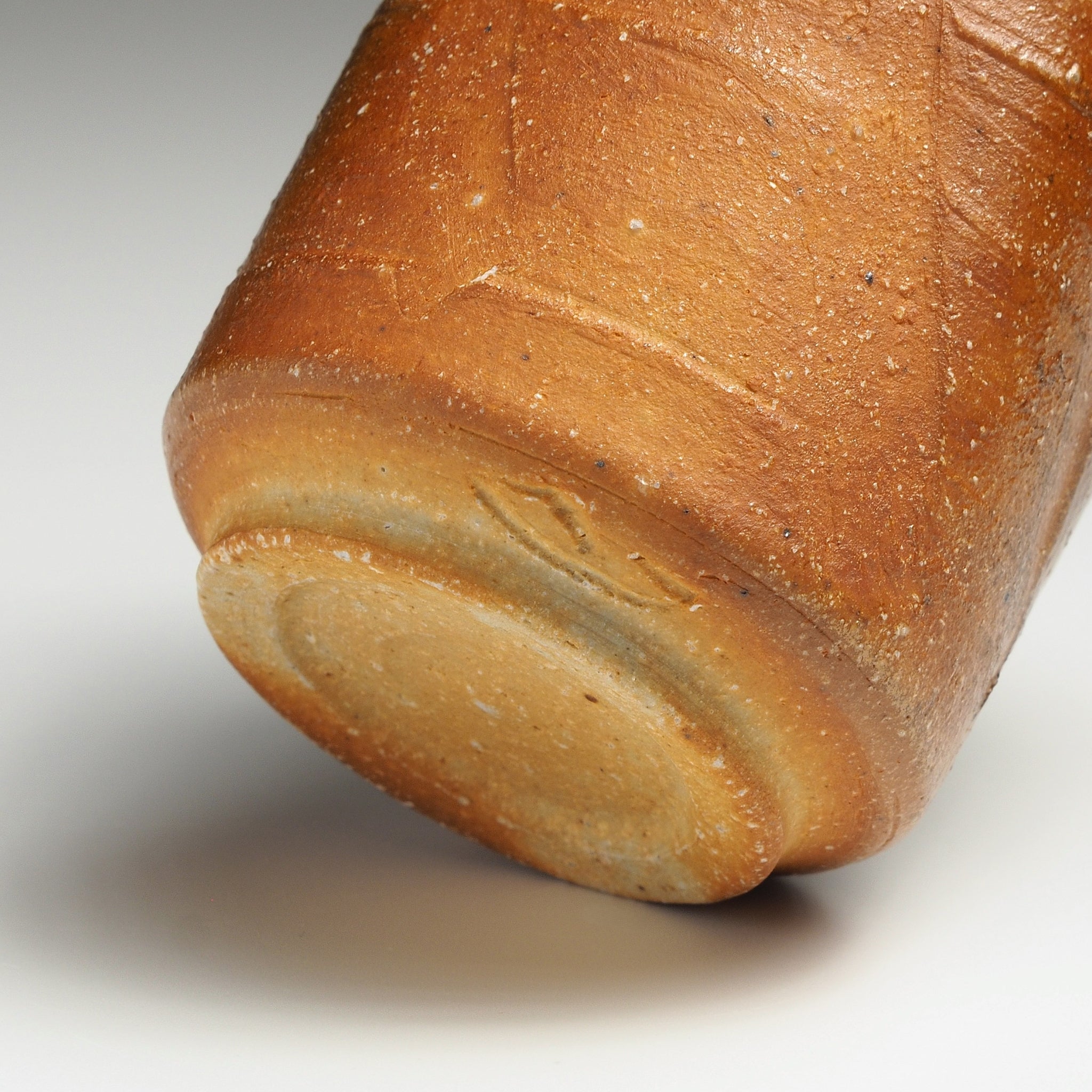 Close-up of the base of a Yubae handmade Shigaraki yunomi showing its foot ring and natural firing marks.