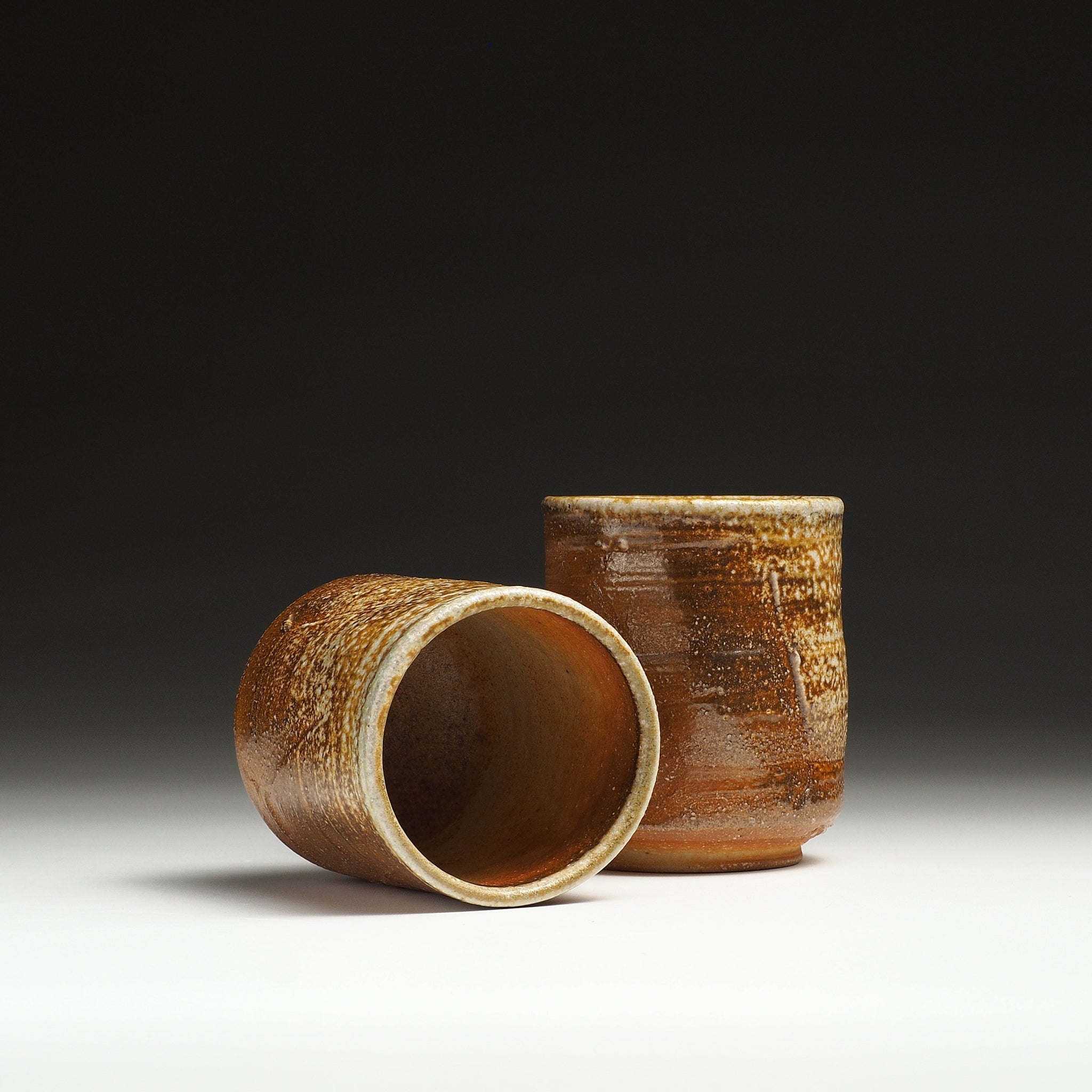 Yubae Shigaraki yunomi set with one teacup lying on its side and the other standing upright.