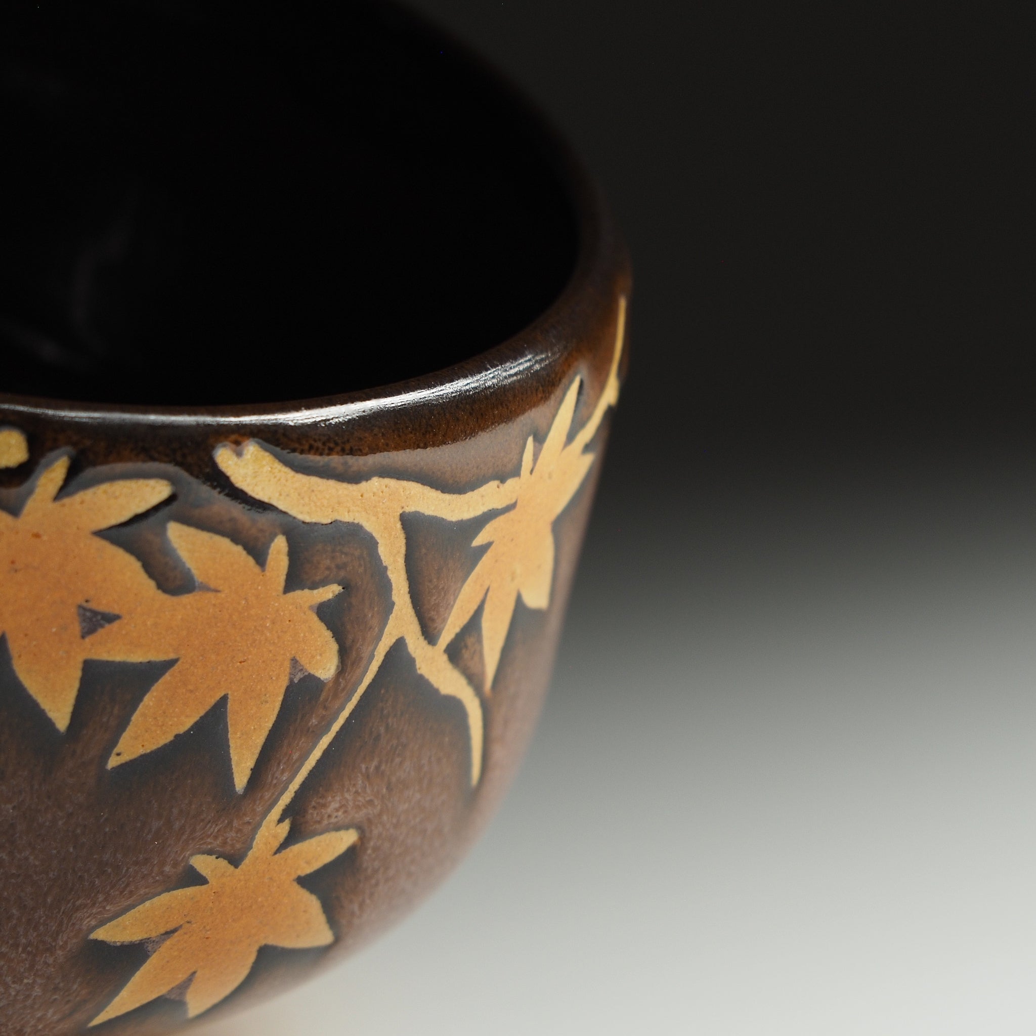 Detail of Yūkaede matcha bowl, momiji maple branch in negative-space natural clay against Nanasai Tenmoku glaze, Nunobiki Kiln