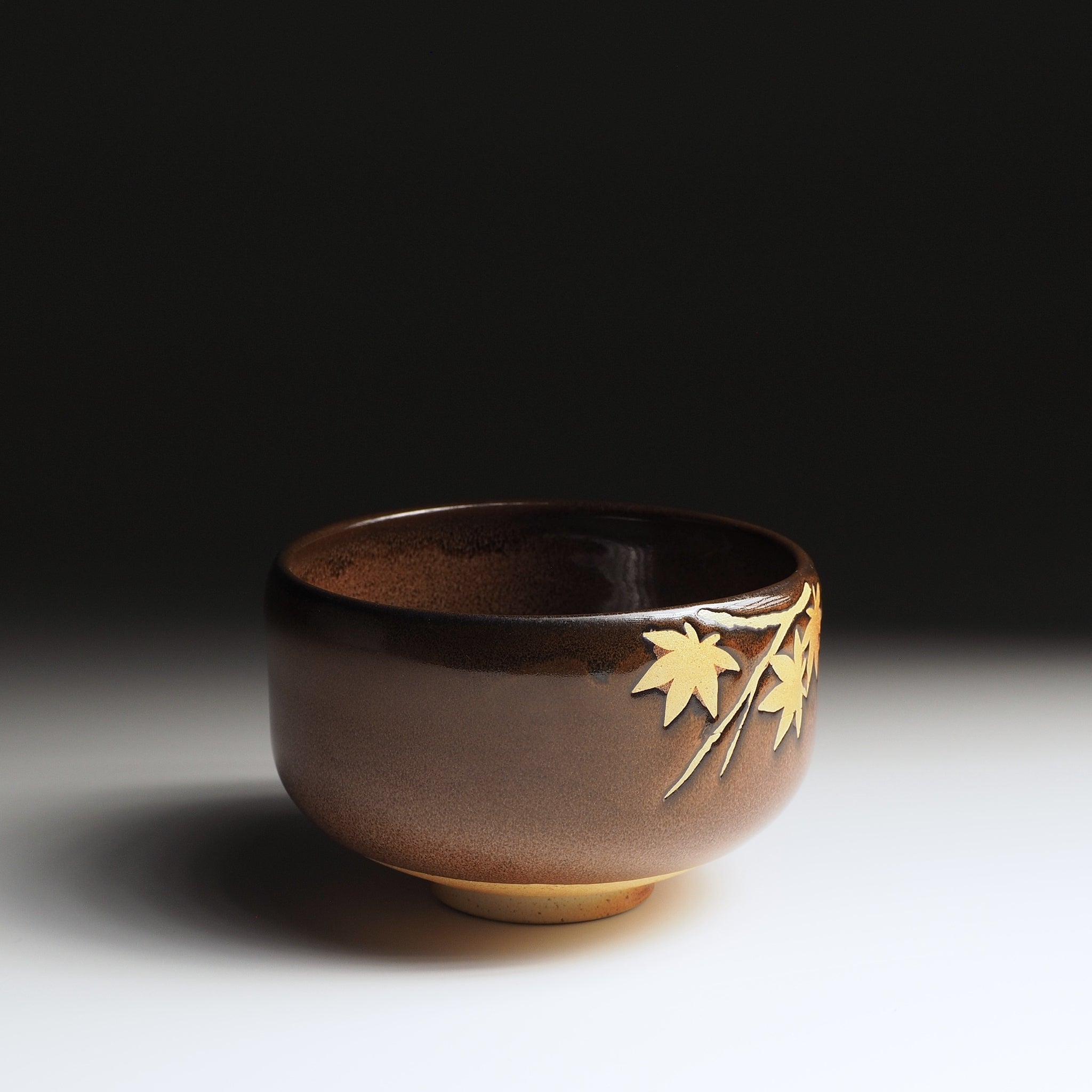 Yūkaede matcha bowl, opposite side view, single momiji sprig in natural clay on Nanasai Tenmoku glaze, Nunobiki Kiln