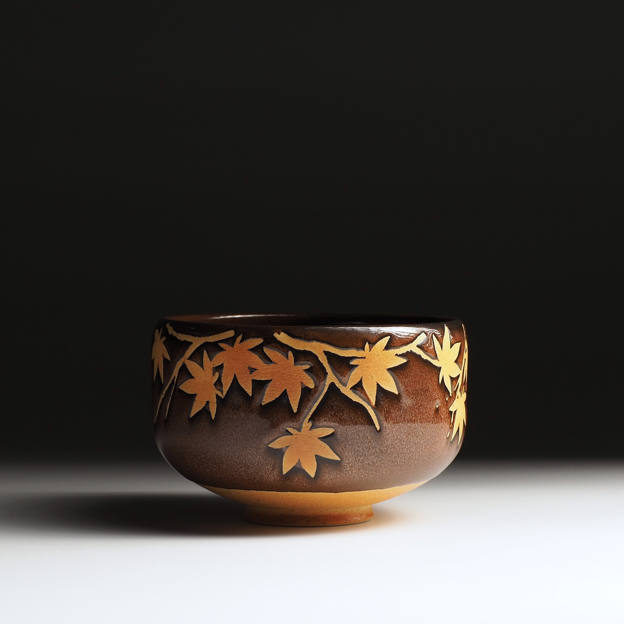 Yūkaede matcha bowl, full front view, cascading momiji decoration encircling the bowl, Nanasai Tenmoku glaze, Nunobiki Kiln